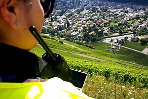 Drohnenpilotin oberhalb eines steilen Rebbergs