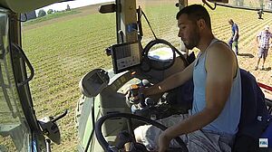 Mann im Traktorführerstand im Zuckerrübenfeld