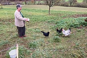 Die Protagonistin füttert Hühner auf der Weide