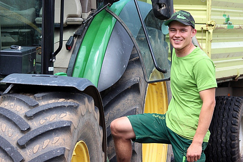 Junger Mann steht neben einem Traktor.