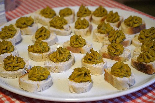 Kleine Scheiben Brot mit Hummus.