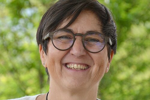 Eine Frau vor grünem Hintergrund. 