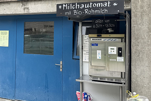 Ein Milchautomat neben einer Stalltüre. 