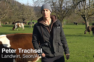 Landwirt Peter Trachsel steht auf einer Weide mit Milchkühen und berichtet über das Weidemanagement auf seinem Betrieb.