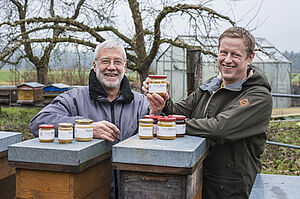 Zwei Männer vor zwei Bienenständen