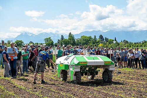Besucher betrachten den Jätroboter bei der Arbeit