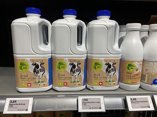 Plastic-Milchflaschen in einem Regal aufgereiht.