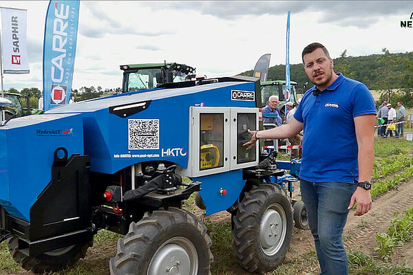 Mann vor allradgetriebenem Fahrzeug mit Hackgerät am Heck