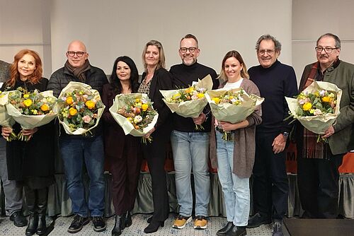 Eine Gruppe von Menschen mit Blumensträussen. 