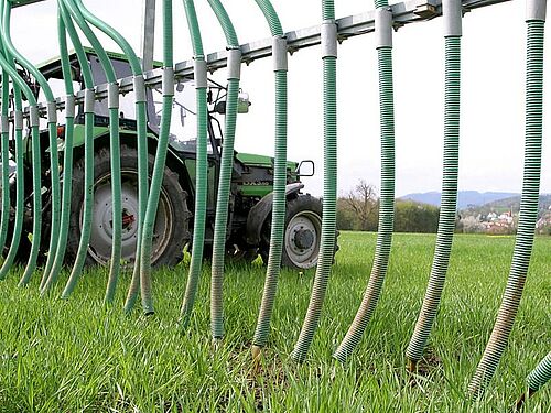 Traktor mit Schleppschlauch beim Güllen einer Wiese