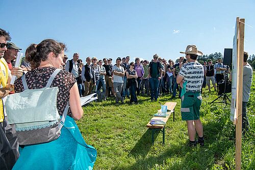 Besucher auf dem freien Feld lauschen den Ausführungen des Beraters