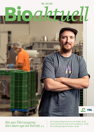 Titelseite Bioaktuell 10|25: Ein Mann schaut mit verschränkten Armen in die Kamera, im Hintergrund ist eine Person an einer Anlage am Arbeiten.