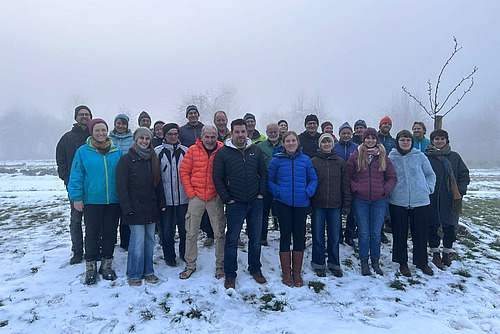 Gruppe von Menschen steht im Schnee.