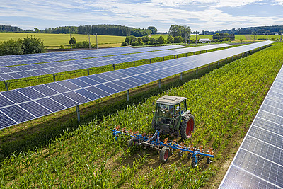 Agri-PV-Anlage in einem Acker mit Traktor.
