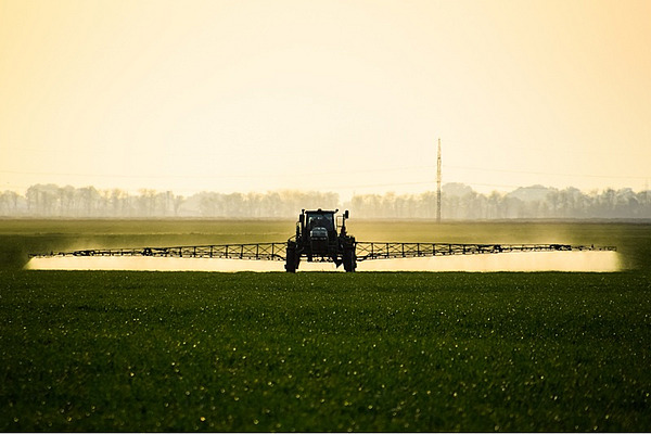 Ein Traktor mit einer Feldspritze auf einem Feld.