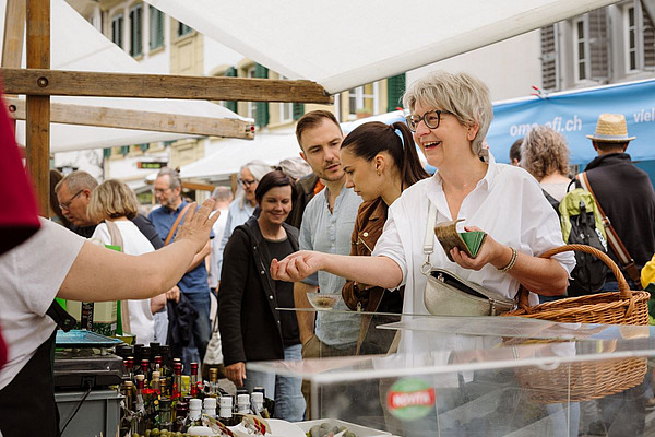 Frau kauft ein Produkt an einem Marktstand.