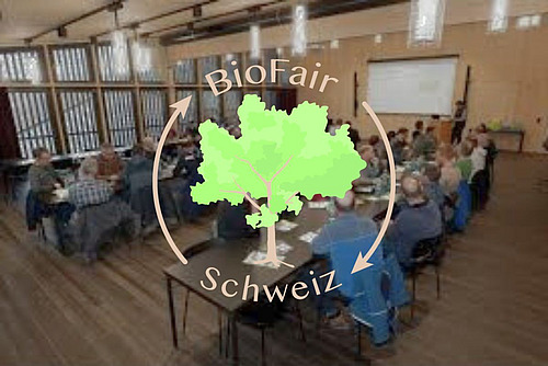 Ein Bild aus einer Versammlung mit einem Logo darüber.