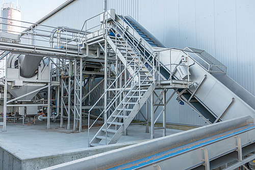 Eine an einem Gewerbegebäude angebaute Struktur mit Leitungen und Treppen.