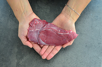 Zwei Hände halten ein Stück Fleisch