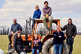 Das Team posiert auf einem roten Traktor auf einem Feld.
