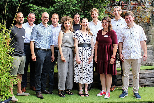 Ein Gruppenbild mit 11 sommerlich gekleideten Menschen. 