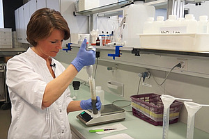 Person im Labor mit Pipette.