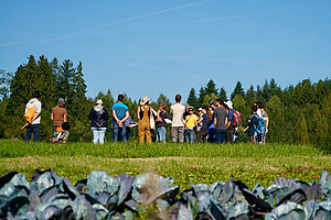 Eine Gruppe Menschen steht auf einem Feld und diskutiert.