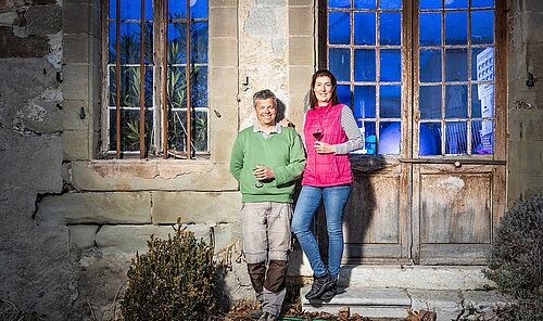 Ein Mann und eine Frau vor einem Gebäude mit einem Glas Rotwein in der Hand