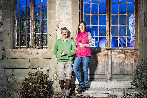 Ein Mann und eine Frau vor einem Gebäude mit einem Glas Rotwein in der Hand