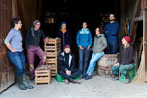 Eine Gruppe von Menschen unterschiedlichen Alters in einer Tenne. 