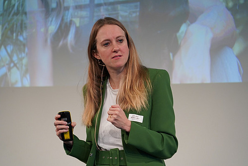 Eine Frau referiert vor einer Powerpoint-Präsentation.