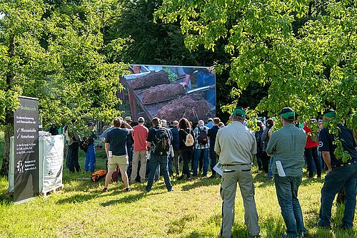 Besucher des Bioackerbautages zwischen Bäumen beim Betrachten von Spatenproben