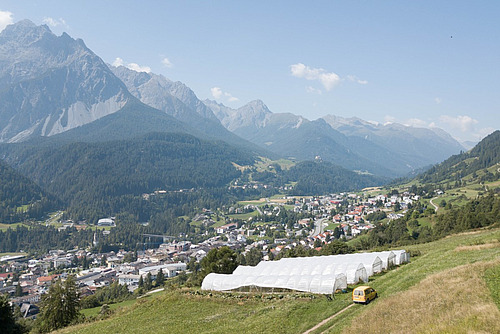 Folientunnel in einer Berglandschaft über einem Dorf.