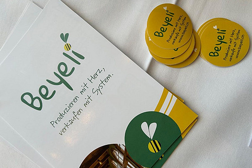 Flyer und Aufkleber mit dem Schriftzug der Beyeli-App.