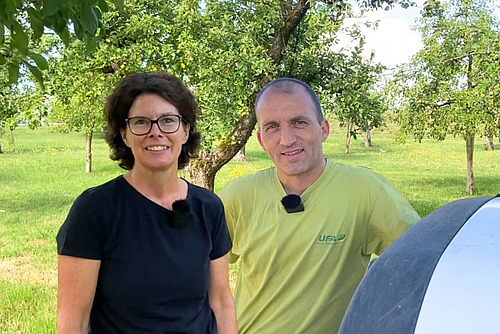 Eine Frau und ein Mann in einem Obstgarten.
