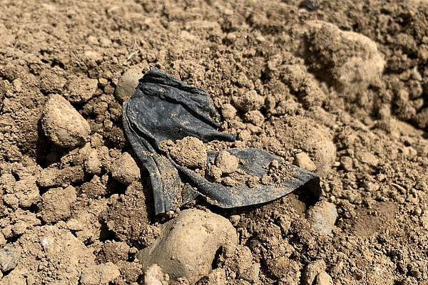 Ein Stück Plastik auf einem Ackerfeld.