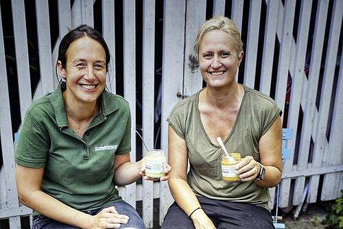 Zwei Frauen halten Gläser mit Hummus.