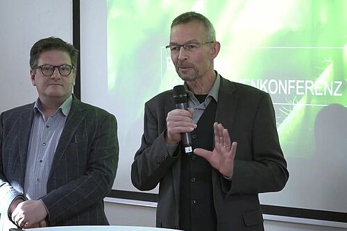 Zwei Personen präsentieren vor einer Leinwand