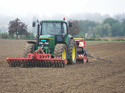 Ein Traktor und eine Sämaschine auf einem frisch bearbeitetem Boden