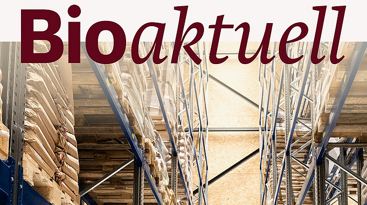 Titelseite Bioaktuell 6|25: Eine Lagerhalle gefüllt mit braunen Säcken, in der Mitte ein Gabelstapler und eine Mann.