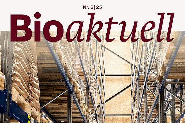 Titelseite Bioaktuell 6|25: Eine Lagerhalle gefüllt mit braunen Säcken, in der Mitte ein Gabelstapler und eine Mann.