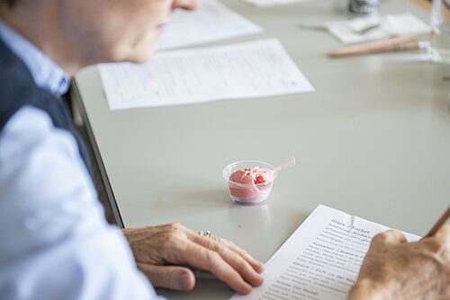 Eine Person füllt einen Fragebogen aus, daneben steht ein Becher mit einer Eiskugel. 