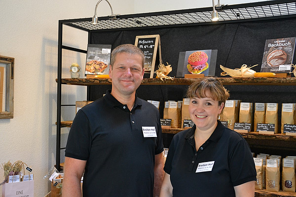 Ein Mann und eine Frau posieren in einem Hofladen. 
