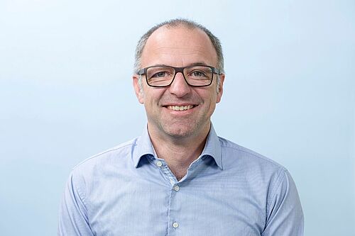 Porträtfoto, Herr Günter mit Brille und blauem Hemd