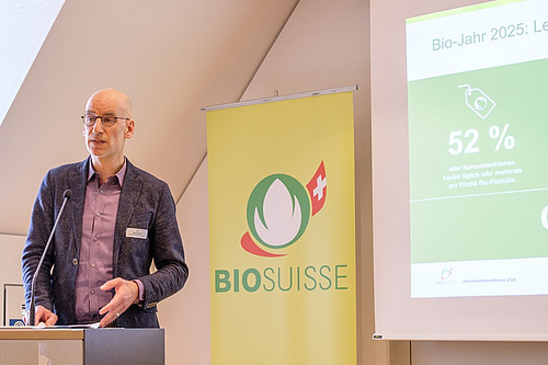 Ein Mann referiert vor einer Powerpoint-Präsentation. 
