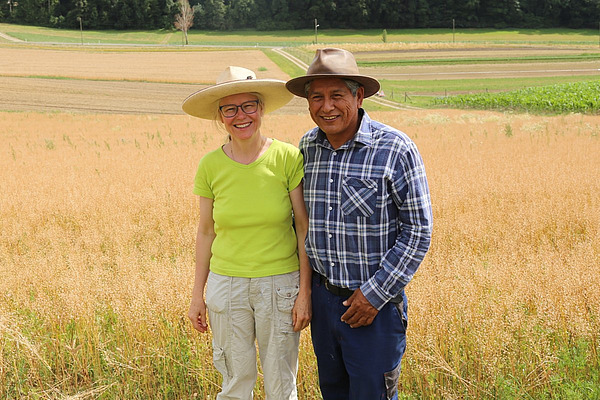 Eine Frau und ein Mann, beide mit Hut, posieren vor einem reifen Getreidefeld.