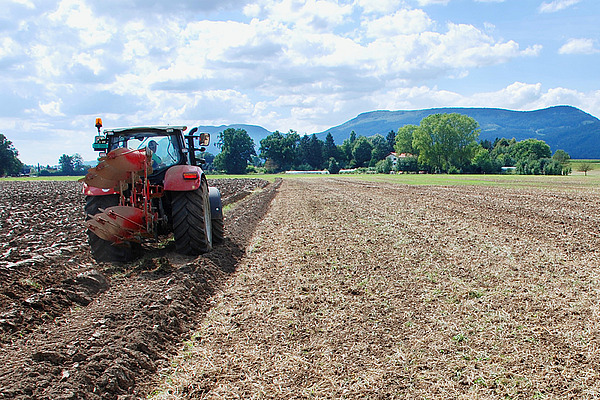 Ein Traktor fährt über ein flach bearbeitetes Feld