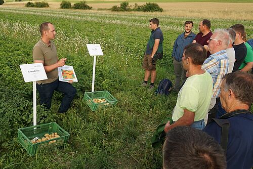 Tobias Gelencsér erklärt einigen Zuhörern auf dem Feld die Sortenversuche