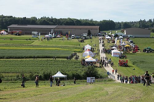 Überblick über das Messegelände mit Ständen und Besuchern auf freiem Feld