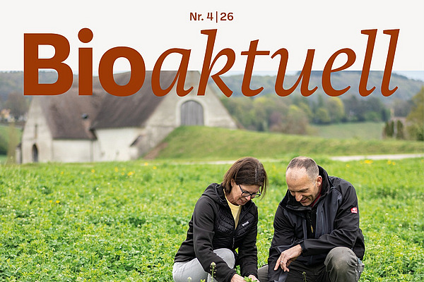 Titelseite Bioaktuell 4|26: Ein Mann und eine Frau kauern in einem Feld.